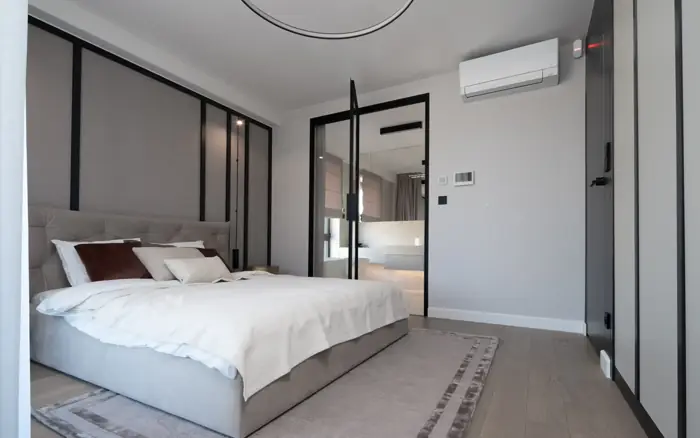 Hotel bedroom with a sliding partition, air conditioning unit and fitted joinery.